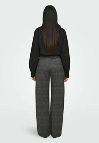 Schwarzes Langarmshirt kombiniert mit grauen Karohosen im weiten Schnitt. Beide Kleidungsstücke haben eine lockere Passform und eine glatte Stofftextur.