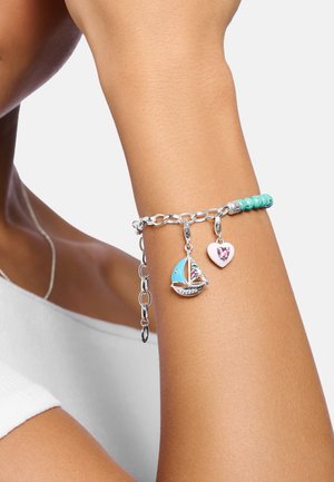 Silver chain bracelet with turquoise beads. Charms include a blue sailboat and a pink heart with rhinestones, featuring colorful nautical details.