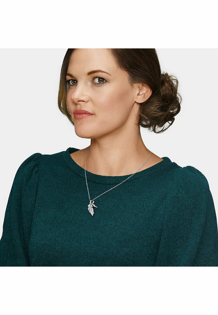 Collana d'argento con pendant a forma di foglia, indossata da una persona con un maglione texture color turchese. Il pendant presenta dettagli intricati che ne esaltano il design.