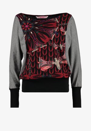 Langærmet, flerfarvet top med blomster- og sommerfuglemønstre, kombineret med hvide skinny bukser og en sølvfarvet, tekstureret tote taske.