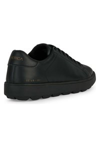 Černé kožené tenisky s hladkým povrchem, zaoblenou špičkou, plochým šněrováním a texturovanou černou gumovou podrážkou. Zlaté logo na patě.