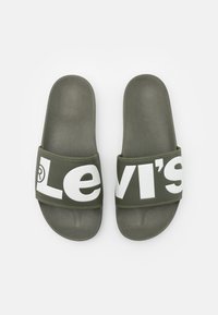 Sandales vertes avec une semelle intérieure texturée et une large sangle arborant le logo « Levi's » en blanc. Design durable et léger.