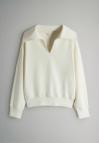 Kreminės spalvos džemperis su gilia V formos iškirpte, dideliu apykakliu ir ribinėmis rankogaliais. Pagamintas iš minkštos, tekstūruotos medžiagos, laisvo silueto.