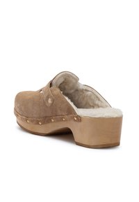 Braune Wildlederclogs mit einem flauschigen Innenfutter, Holzplattform und goldenen dekorativen Nieten entlang des Randes. Offenes Rückendesign für ein einfaches An- und Ausziehen.
