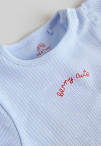 Body per bambini azzurro chiaro a coste con pois bianchi e ricamo rosso con la scritta "berry cute" sul petto.