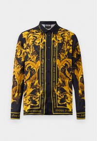 Camicia a maniche lunghe con base nera e motivi dorati ornamentali e testo. Realizzata in tessuto morbido, con colletto classico e chiusura con bottoni.