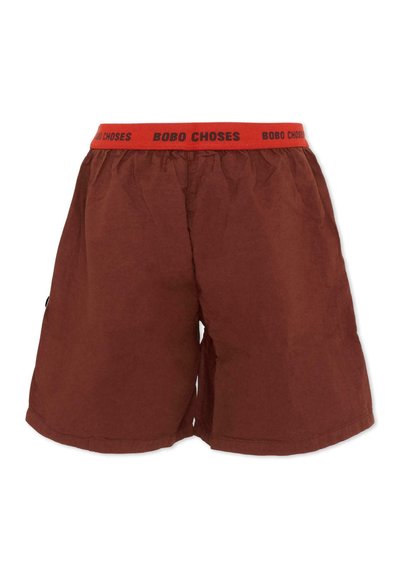 Pantaloncini marroni a taglio largo con girovita elastico rosso riportante la scritta nera "BOBO CHOSES" ripetuta.
