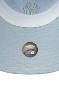 Cappello di stoffa blu chiaro con visiera bianca. Presenta un adesivo della Major League Baseball con cuciture rosse, dettagli del produttore e loghi.