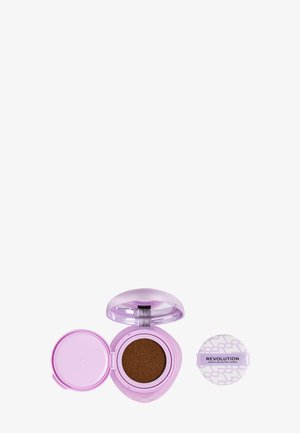 Trousse de maquillage rose compacte avec fond de teint cushion brun foncé et houppette ronde blanche séparée de la marque « Revolution ».