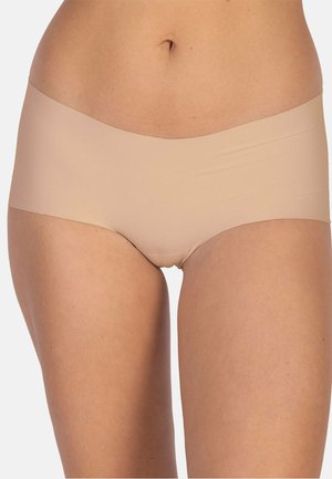 Beige nahtlose Hipster-Unterwäsche, die an der unteren Taille und an den Oberschenkeln einer Frau getragen wird, vor einem weißen Hintergrund gezeigt.