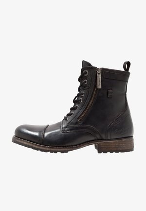 Stivaletto in pelle nera con chiusura frontale con lacci, cerniera laterale, tacco impilato marrone e linguetta sul retro.