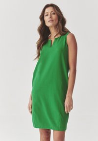 Green sleeveless dress with a V-shaped neckline, knee-length design, smooth fabric texture, and side slits for ease of movement.
