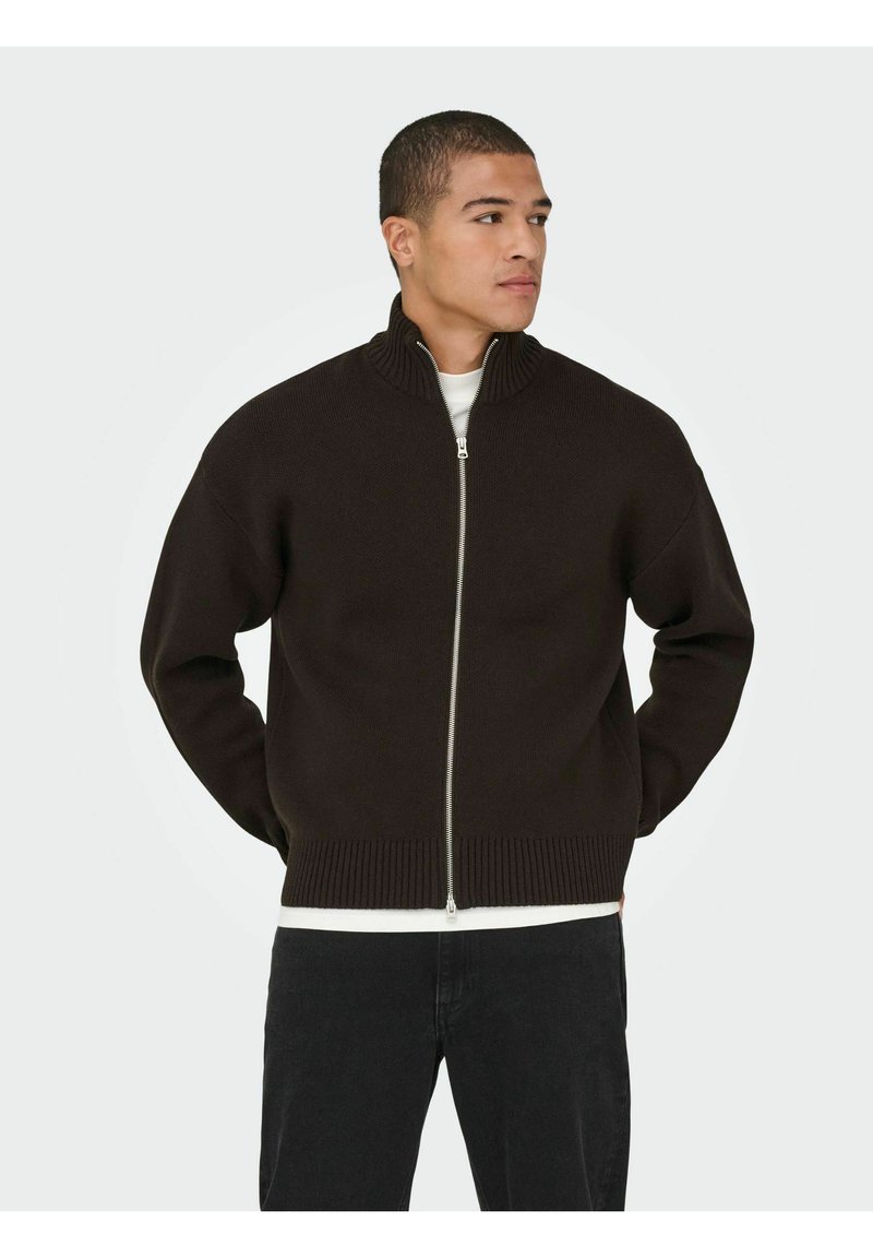 Pull marron foncé à fermeture éclair avec un col montant et des poignets côtelés. Présente une texture lisse et une couche intérieure blanche contrastante.