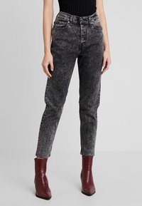 Svarta högmidjade jeans i denim med en blekt tvätt, med fem fickor, bältesloopar och råa fållar, ihopparade med bordeauxfärgade texturerade ankelstövlar.