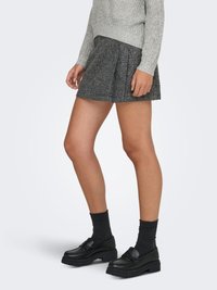 Siva mini suknja s teksturom i nabranim naborima, uparena s crnim platformama i tamnim rebrastim čarapama, postavljena na neutralnoj pozadini.