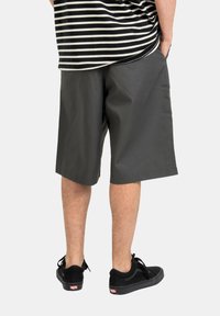 Gray shorts with a straight cut, knee-length, made of solid fabric. Worn with black sneakers featuring a classic design and logo.
