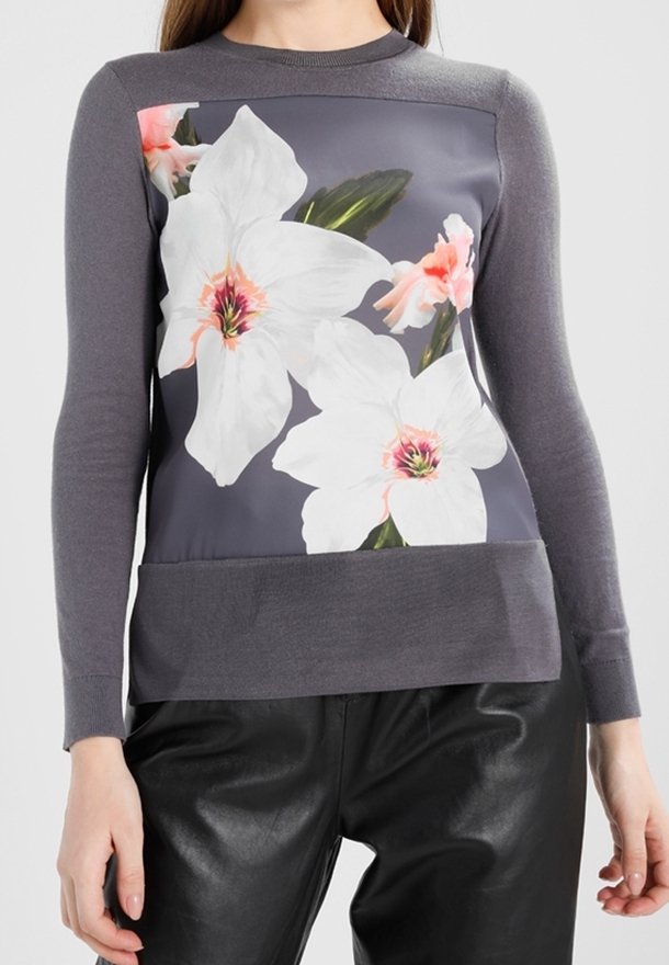 Grå tröja med snugga långa ärmar, prydd med en blommig grafik i vitt och rosa på framsidan och en enfärgad grå ribbad fåll.