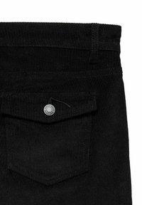 Pantalons en velours côtelé noir avec une surface texturée, une taille basse et une fermeture à bouton métallique au-dessus d'une poche arrière.