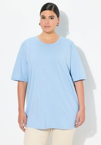T-shirt oversize azzurro chiaro realizzato in tessuto morbido, con scollo rotondo e maniche corte, dalla texture liscia e semplice.