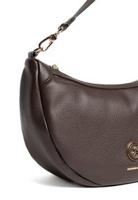 Bolso de mano de cuero marrón con forma curva de media luna. Presenta un logo dorado y una correa ajustable con un broche. Detalle de superficie texturizada.