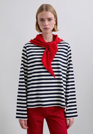 Top de manga larga a rayas en azul marino y blanco, con una bufanda roja anudada al cuello. Combinado con pantalones rojos. Tejido de algodón suave.