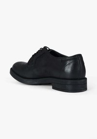 Scarpa nera in pelle con tacco basso, punta tonda e delicati dettagli di cucitura. Il modello con lacci è completato da una texture liscia.