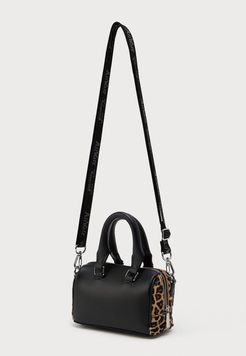 Kleine schwarze Handtasche mit Leopardenmuster an den Seiten, zwei oberen Griffen und einem abnehmbaren schwarzen Schultergurt mit weißem Text.