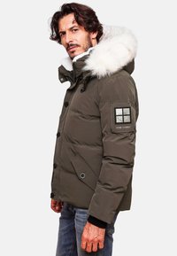Puffer jacket in olive green with a white fur-lined hood, button front, side pockets, and a black patch on the arm with branding details.