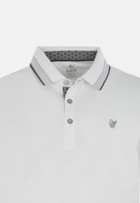 Polo bianco con apertura a due bottoni. Presenta un colletto e un motivo interno grigio. Include un piccolo logo ricamo sul petto.