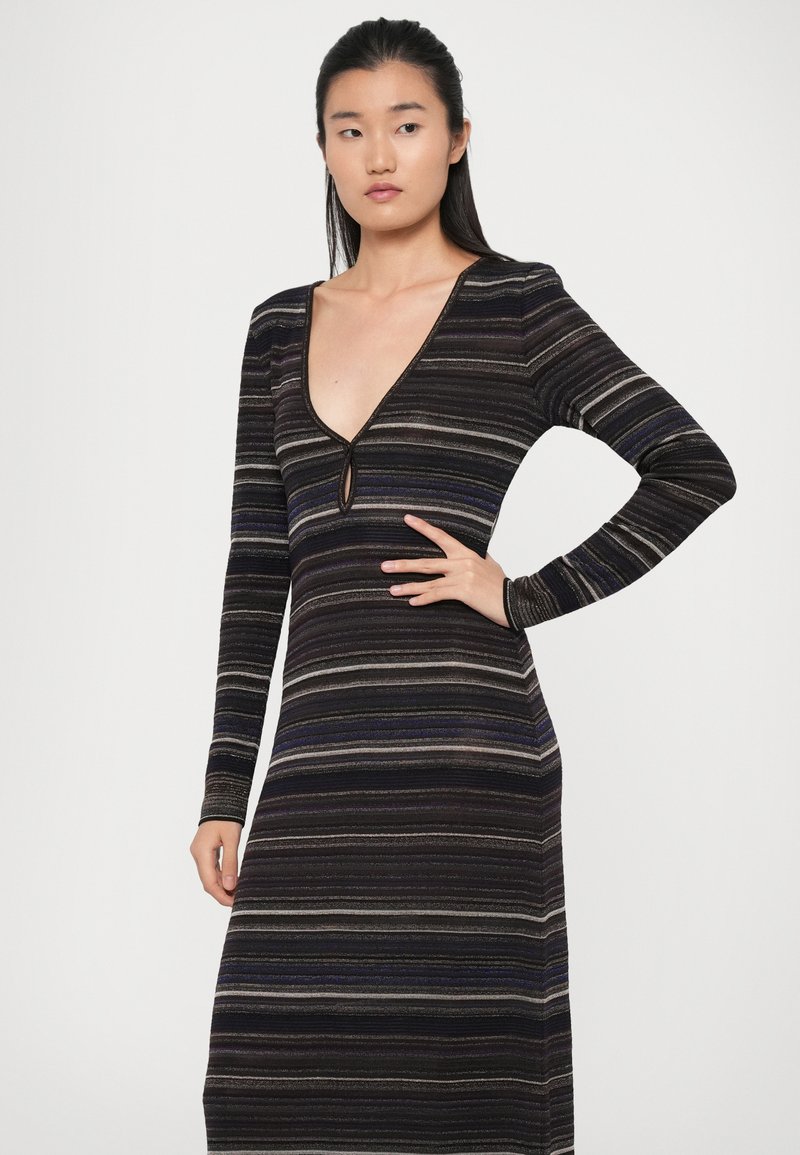 Robe en tricot à manches longues, décolleté en V profond et détail en trou de serrure. Présente des rayures horizontales dans des tons de noir, gris et bleu. Silhouette ajustée.