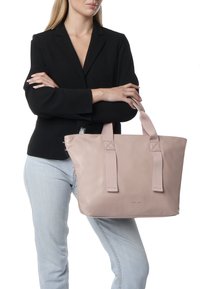 Sac fourre-tout en cuir rose avec des poignées en tissu doubles et des accents cousus. Texture douce, forme rectangulaire, mis en valeur sur un fond neutre.