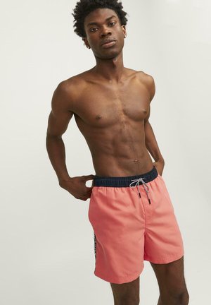 Koraal kleurige zwemboxers met een marineblauwe elastische tailleband, een trekkoordsluiting en zijstrepen, gemaakt van lichte, sneldrogende stof.