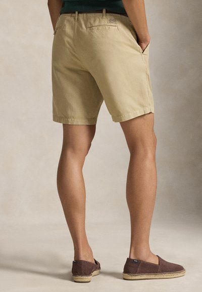 Μπεζ βαμβακερά σορτς με άνετη γραμμή, που φτάνουν μέχρι το μέσο του μηρού. Διαθέτουν δύο πλευρικές τσέπες και μια πίσω τσέπη με ραφές ως λεπτομέρεια. Καφέ εσπαντρίγιες.