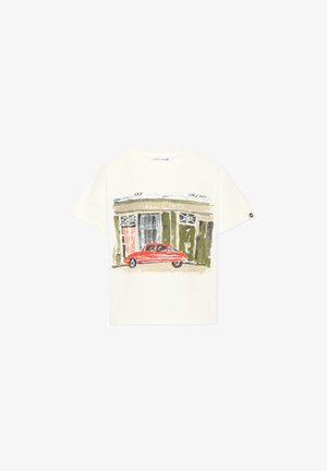 T-shirt blanc à manches courtes avec un motif peint d'une voiture vintage rouge devant un bâtiment vert et beige.