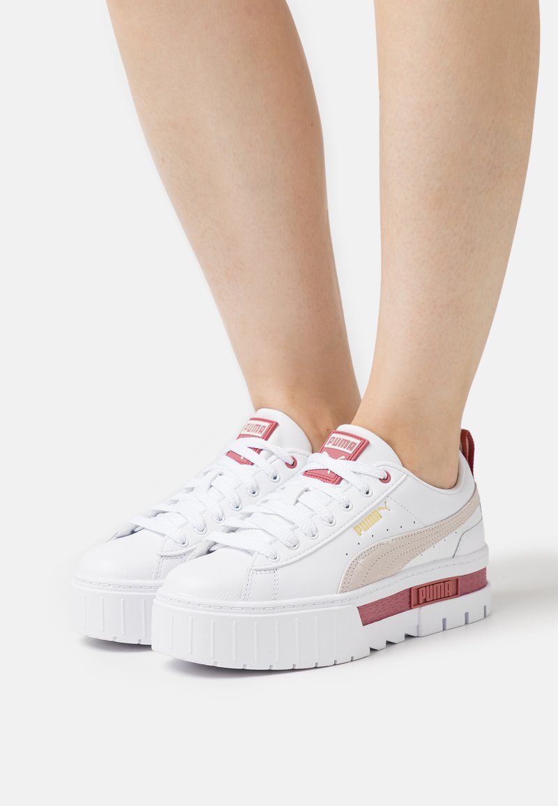 Sapatilha branca com pele texturizada, sola plataforma, detalhes em rosa e dourado, e design de atacadores. Marca PUMA na língua e na lateral.