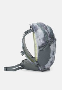 Mochila con un patrón gris y negro, con soporte trasero de malla, acentos amarillos, correas ajustables y múltiples compartimentos para almacenamiento.