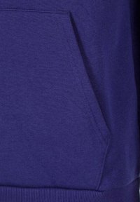 Nahaufnahme einer dunkelblauen Stofftasche an einem Kleidungsstück, die Textur und Nähdetails zeigt.