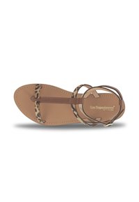 Sandale plate avec une semelle en cuir brun et des sangles à imprimé léopard. Dispose d'une sangle au milieu du pied et d'une sangle de cheville avec une boucle dorée.