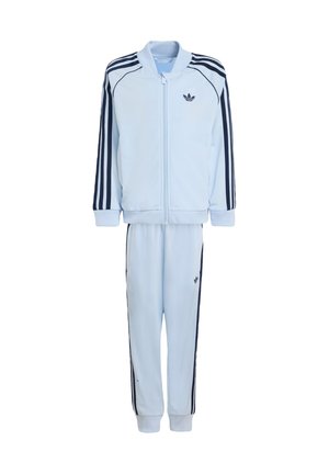 Survêtement bleu clair en polyester lisse, avec des rayures latérales bleu marine, col et poignets côtelés, veste zippée à l'avant, et pantalon à taille élastique.