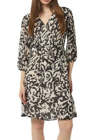 Sukienka drukowana z dekoltem w szpic, rękawami o długości trzech czwartych i ściągniętym w talii. Materiał z abstrakcyjnym wzorem w kolorze czarnym i kremowym.
