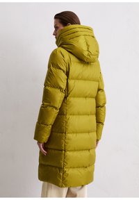 Olijfgroene pufferjas met een volledige capuchon, met een gecapitonneerd ontwerp en lange mouwen, tot halverwege de dij. Gladde, glanzende textuur.