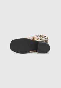 Sandalia multicolor con una parte superior de tela con estampado y un detalle de hebilla, y una suela de goma negra sólida para agarre y estabilidad.