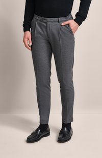 Grau maßgeschneiderte Hosen aus strukturiertem Stoff, mit Bundfalten, seitlichen Taschen und einem geraden Bein. Kombiniert mit schwarzen Slippers.