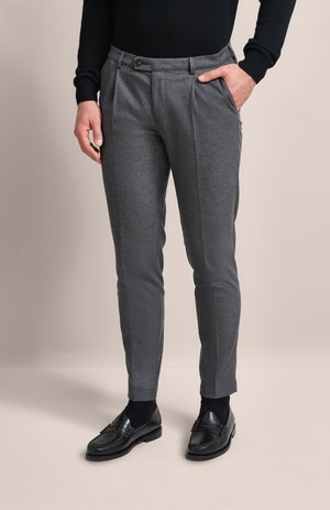 Grau maßgeschneiderte Hosen aus strukturiertem Stoff, mit Bundfalten, seitlichen Taschen und einem geraden Bein. Kombiniert mit schwarzen Slippers.