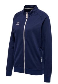 Marineblå zip-up jakke lavet af blødt stof, med høj krave, kontrastlynlås, sidelommer og logo på brystet.