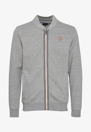 Grå genser med glidelås og høy krage, ribbestrikkede mansjetter og hem. Har en lett glidelås og en liten logo på brystet. Myk tekstur.