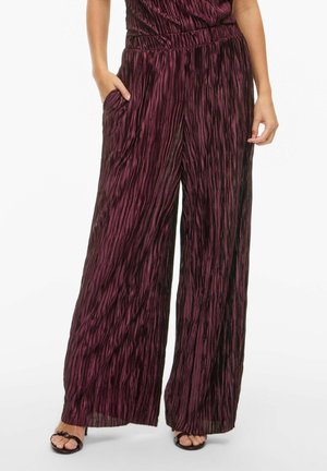 Pantalons larges en velours côtelé de couleur bordeaux avec un design plissé texturé, dotés de poches latérales et d'une taille élastique.