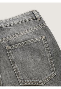 Jeans de mezclilla gris con un bolsillo trasero con costuras decorativas, textura desgastada y una cinturilla con un pequeño lazo en la parte superior.