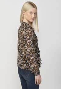 Blusa paisley multicolore con ruffles, caratterizzata da uno sfondo nero, maniche lunghe e tessuto morbido e leggero.