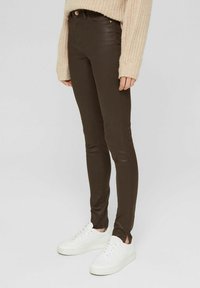 Bruna skinny jeans i denim, med en medelhög midja, rena linjer och en slät yta, parat med vita sneakers.